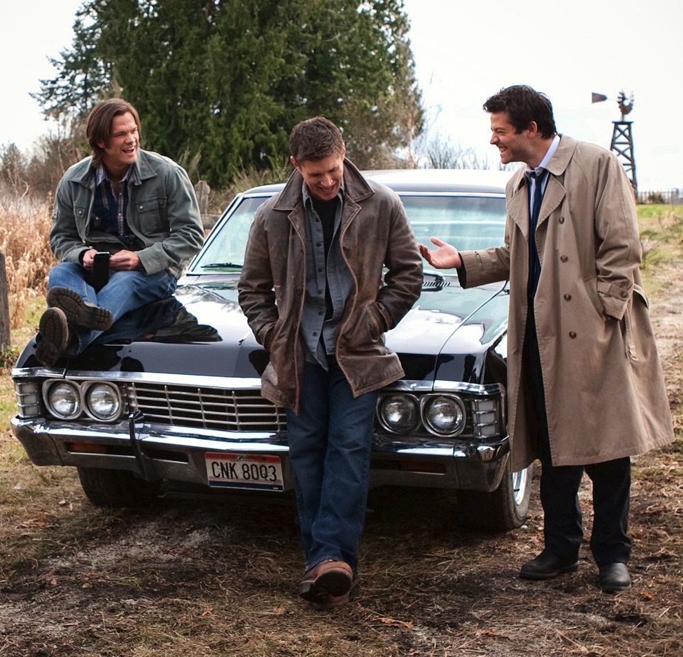 Sam, Dean, and Castiel from CW's Supernatural standing in front of the Impala